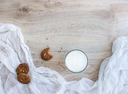 on a wooden table on a white napkin lie oatmeal cookies sunflower seeds toast a glass of milk crumbsの写真素材