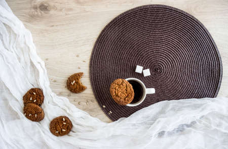 on a wooden table on a white and dark round napkin lie oatmeal cookies Sunflower seeds are a glass of coffee crumbsの写真素材
