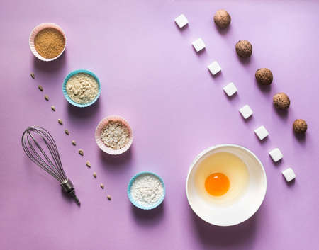 on a lilac background food knolling diagonal walnut greek seeds sunflower sugar cube refined corn spoon egg in a round bowl cake mold flour blue pinkの写真素材