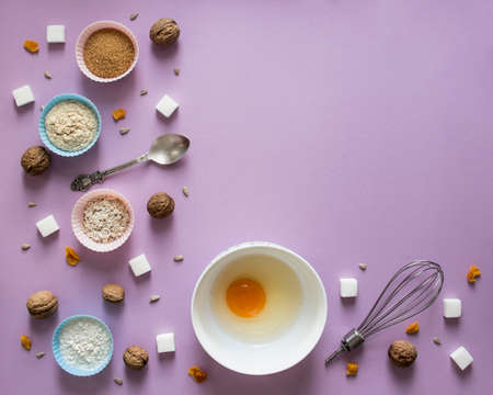on a lilac background dried fruit arrangement chaos mess walnut greek seeds sunflower sugar sugar cube refined corn spoon shape for cupcakes flour blue pink notepad kraft pencil purple egg bowlの写真素材