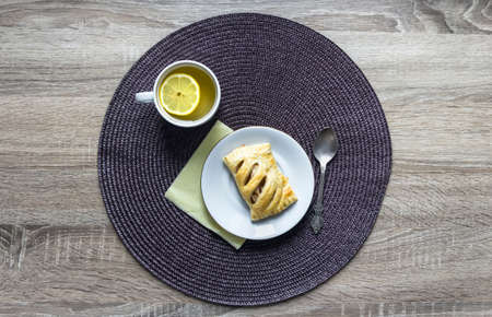 on a wooden background napkin round wicker tea cup lemon saucer puff croissant breakfastの写真素材