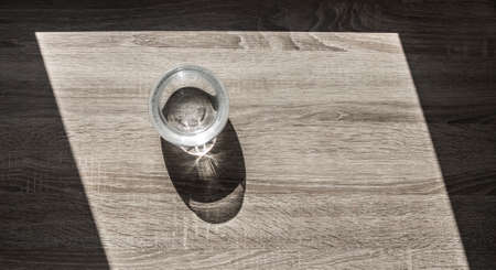 vase with water in air bubbles horizontal on a wooden table glare view from above background shadow trapezoidの写真素材