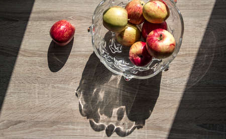 vase with apples horizontal on a wooden table highlight top view background shadow trapezoid apple on the tableの写真素材