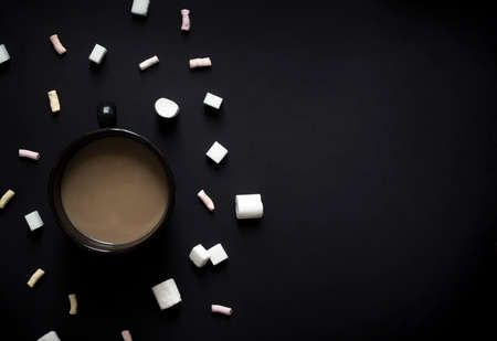 on a black dark background cup of black with coffee and milk marshmallows and sugar vignetting horizontalの写真素材