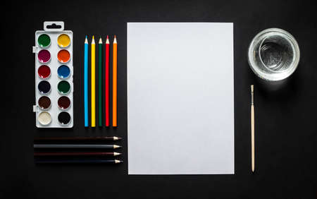 on dark background paint sheet brush pencils colored jar with water horizontal top view flat lay background knollingの写真素材