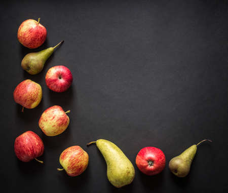 on a dark black background red yellow green apples pear frame top view flat layの写真素材