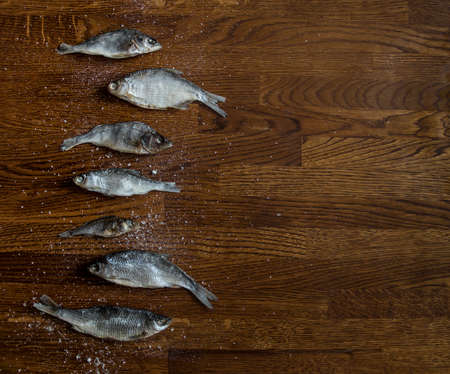on a wooden background of small dark brown on the side lie salted dried fish large saltの写真素材