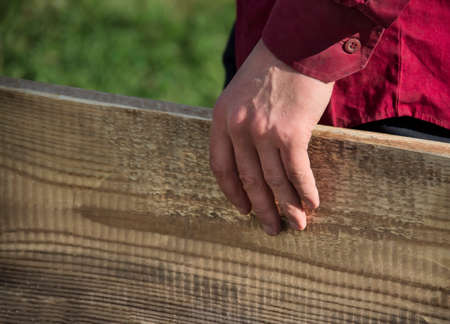 A man's hand in a dark red shirt holds a wooden boardの写真素材