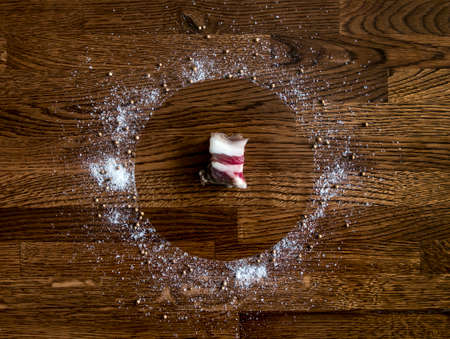 on a dark wooden background of boards of oak piled a circle of salt and pepper and seasonings in the center lies a piece of fatの写真素材
