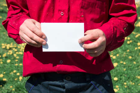 male working hands in a working shirt red burgundy color and pants dark blue holding a white sheet of paper ad rally strike copy spaceの写真素材