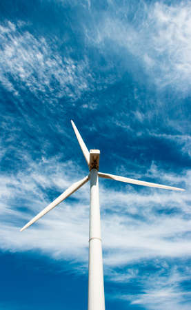 wind generator of electricity from three blades against the background of clouds and blue skyの写真素材