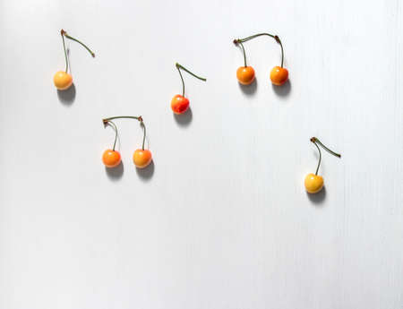 on white background notes from berries sweet cherry yellow red color place inscription music notation camp copy spaceの写真素材