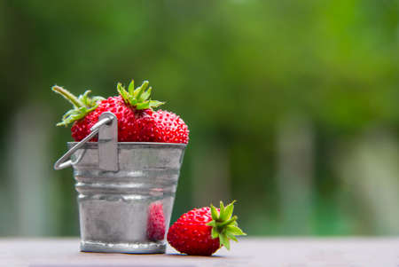 on a green background is a bucket with berries strawberries strawberry red color inscription place copy spaceの写真素材