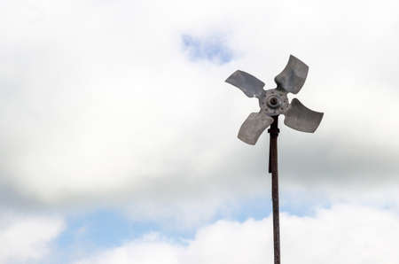wind generator of electricity from four blades against a background of clouds and blue skyの写真素材