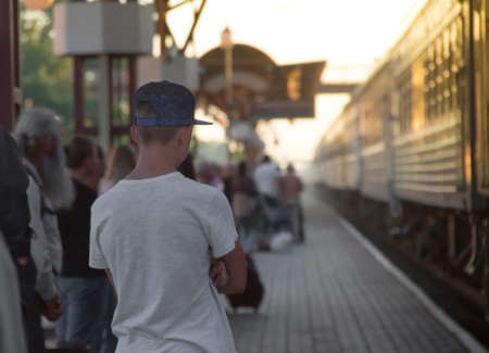 people are standing on a sunset sunset greeting the arrival of the train at the train station seeing off the tank top cap inscription copy spaceの写真素材
