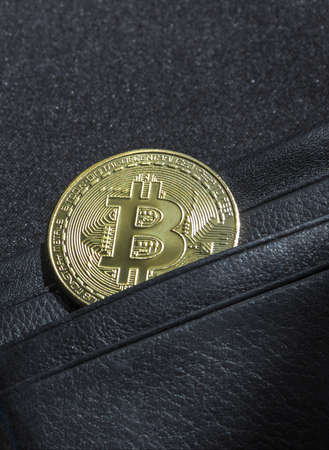 on a black background with a bokeh with sequins is a black leather wallet purse for money with a coin of crypto currency currency bitcoinの写真素材