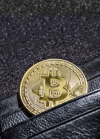 on a black background with a bokeh with sequins is a black leather wallet purse for money with a coin of crypto currency currency bitcoinの写真素材