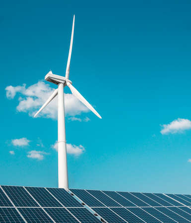 wind generator of electricity from three blades and solar panels of a battery of photocells against a background of clouds and a blue skyの写真素材