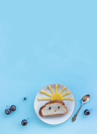 on a blue background breakfast morning sun cloud sky rays rays cute sandwich healthy food berries blueberries plum bread cheese plate spoon servingの写真素材