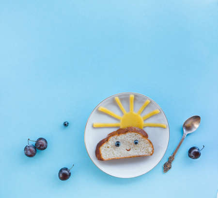 on a blue background breakfast morning sun cloud sky rays rays cute sandwich healthy food berries blueberries plum bread cheese plate spoon servingの写真素材