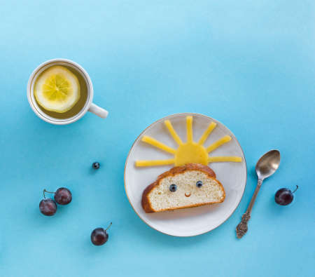 on blue background breakfast morning sun cloud sky rays joy cute sandwich healthy food berries blueberry plum bread cheese plate spoon serving napkin cup tea drinkの写真素材