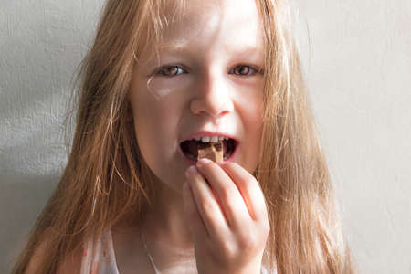 on white background, beautiful girl with long hair eating candyの写真素材