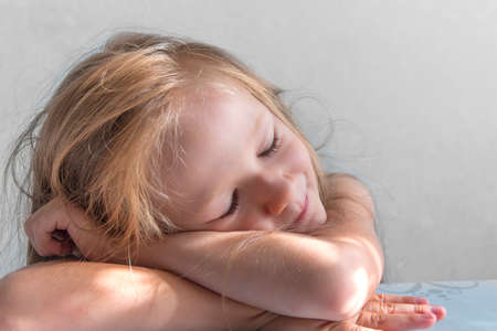 on a gray background a sleeping smiling girl lies in the rays of the sun morningの写真素材