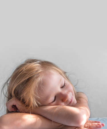 on a gray background a sleeping smiling girl lies in the rays of the sun morningの写真素材