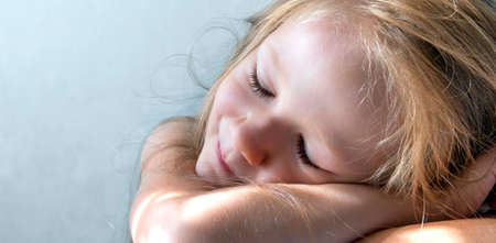 on a gray background a sleeping smiling girl lies in the rays of the sun morningの写真素材