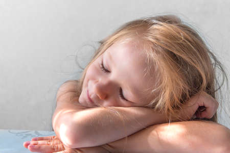 on a gray background a sleeping smiling girl lies in the rays of the sun morningの写真素材