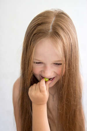 on white background girl eating grape hand feedingの写真素材