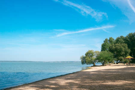 sea sand beach bay blue water sky trees on the shoreの写真素材