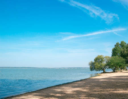 sea ââsand beach bay blue water sky trees on the shoreの写真素材