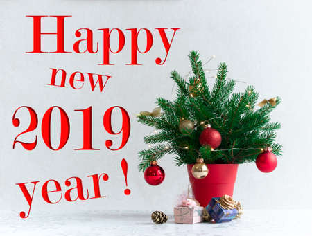 on a light background there is a Christmas decorated tree in a red pot under itの写真素材