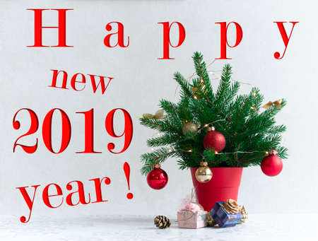on a light background there is a Christmas tree decorated with lights in a red pot under it. Gifts of conesの写真素材