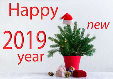 on a light background there is a Christmas tree decorated with lights in a red pot under it. Gifts of conesの写真素材