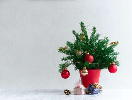 on a light background there is a Christmas decorated tree in a red pot under itの写真素材
