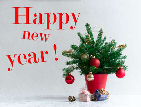 on a light background there is a Christmas decorated tree in a red pot under itの写真素材