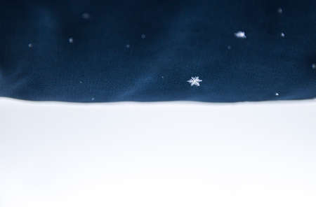 on a dark blue cloth, snow and one clear snowflake on a white background denimの写真素材