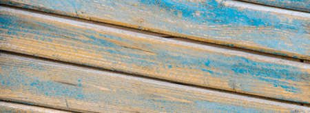 background of wooden slats of planks located on a diagonal of yellow and blue color aged woodの写真素材