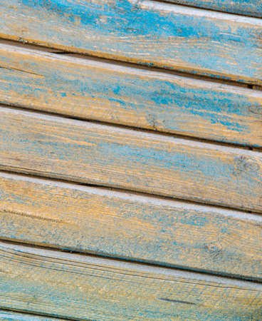 background of wooden slats of planks located on a diagonal of yellow and blue color aged woodの写真素材