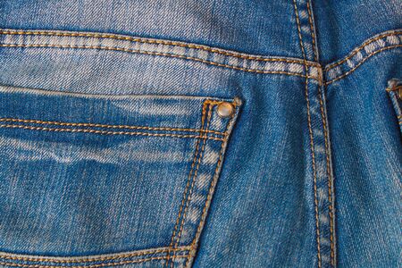 Blank real leather jeans label sewed on old worn blue jeans. Denim background, jeans, closeup surface of denim.の写真素材