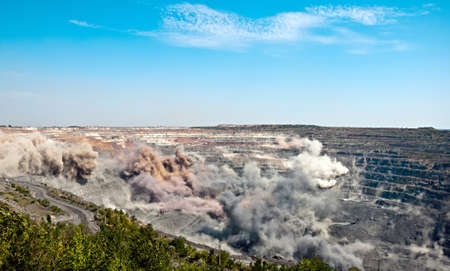 excavators,trucks and heavy technics in open cast mine after blast among dust and smokeの写真素材
