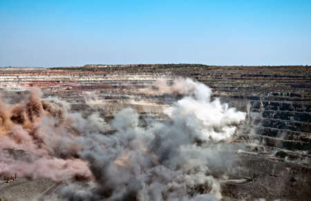 excavators,trucks and heavy technics in open cast mine after blast among dust and smokeの写真素材