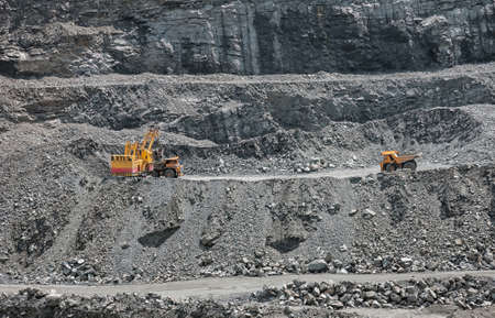 Excavator loading iron ore into the heavy dump truck on the iron ore opencast mineの写真素材