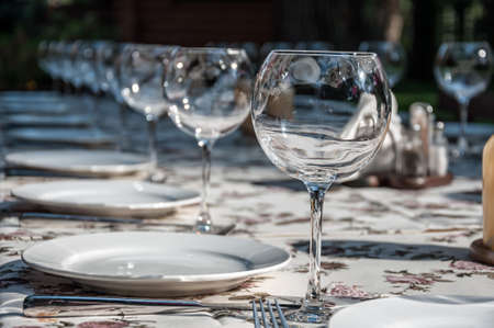 empty footed tumblers,glasses and party plates on festive served tableの写真素材