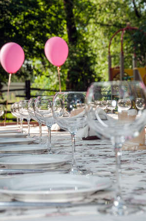 empty footed tumblers,glasses and party plates on festive served tableの写真素材