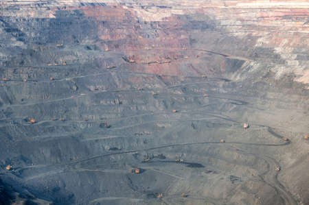 open cast mine extracting iron ore with heavy trucks, excavators, diggers and locomotives