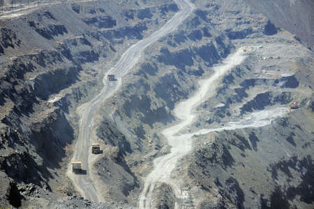open cast mine extracting iron ore with heavy trucks, excavators, diggers and locomotives