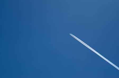 A lone plane in the sky draws a trail